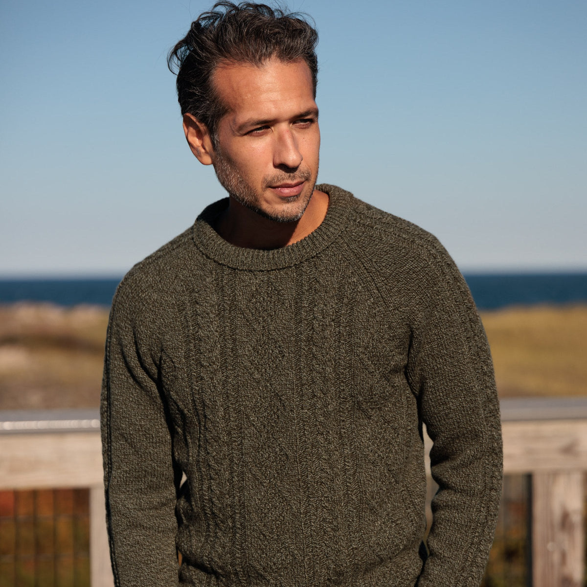 The Ross 4-ply Scottish lambswool cable knit crewneck in Bracken, front view, hand in pocket