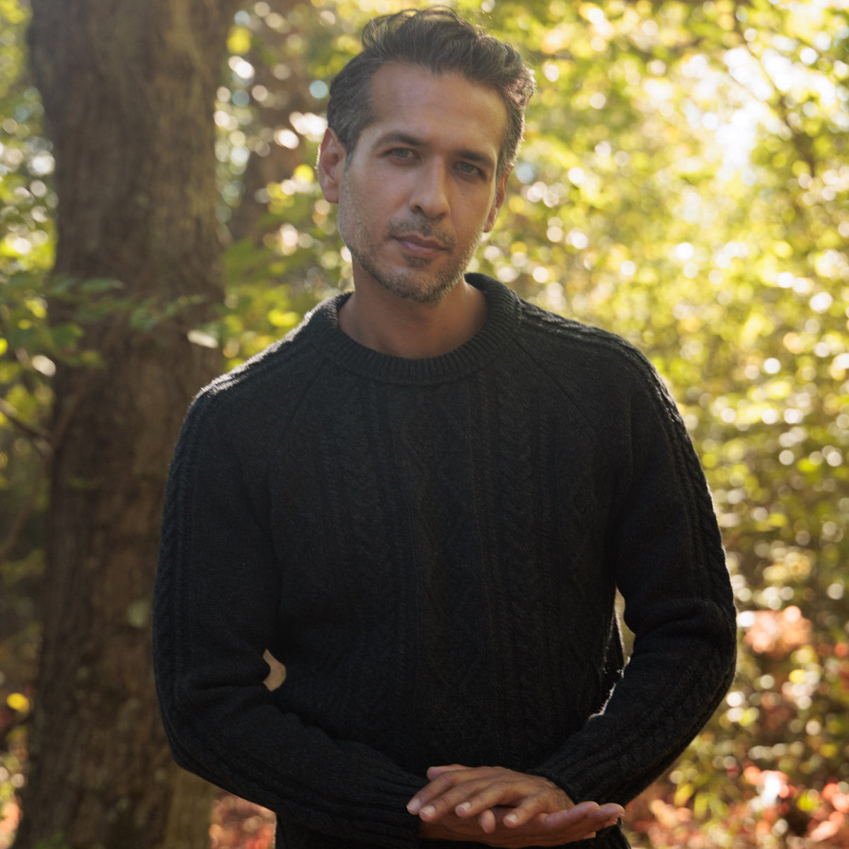 The Ross 4-ply Scottish lambswool cable knit crewneck in Charcoal, in the woods